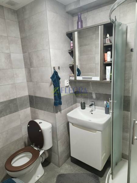 Fürdőszoba egy kétszobás lakásban modern burkolatokkal és zuhanyzóval.