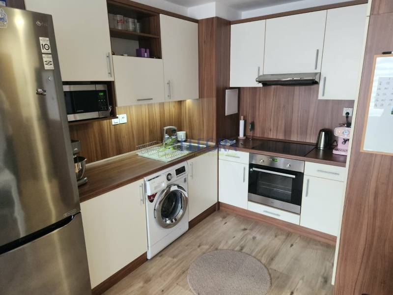 Konyha egy kétszobás lakásban fa dekor padlóval, tűzhellyel és hűtőszekrénnyel.