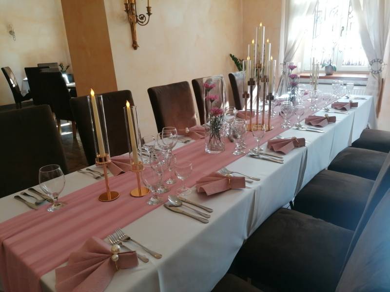 Stílusos belső tér vendégek számára asztallal a szállodákban és panziókban, gyertyákkal és virágokkal díszítve.