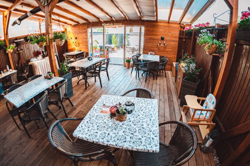 A fapadlós dekorációval rendelkező szállodákban és panziókban asztalok, székek és virágok találhatók.