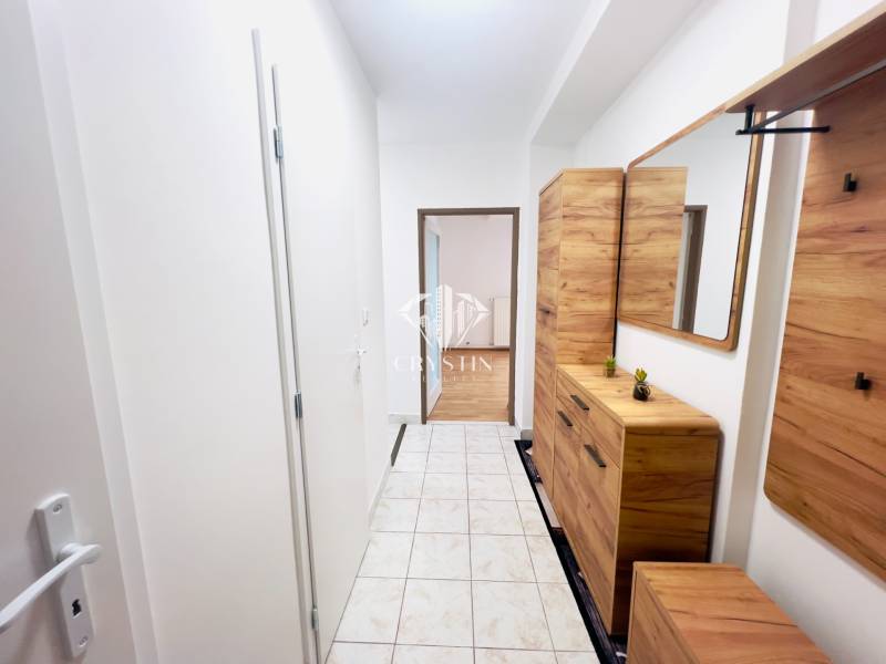 Folyosó egy 2 szobás lakásban csempével és fa dekorációjú bútorokkal.