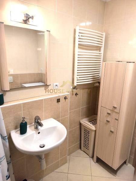 Fürdőszoba mosdóval, tükörrel és szekrénnyel egy kétszobás lakásban.