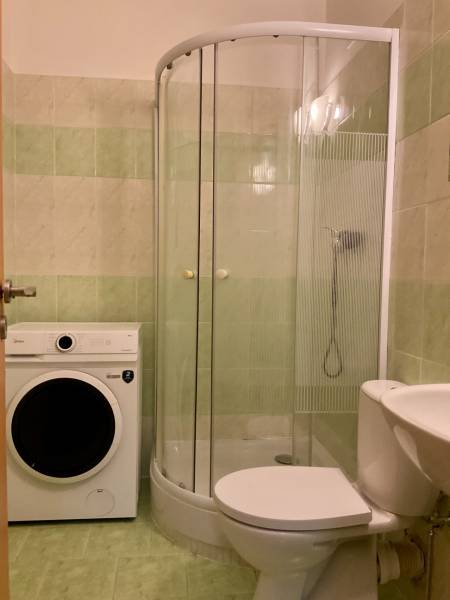 Fürdőszoba mosógéppel, zuhanyzóval és WC-vel a garzonlakásban.