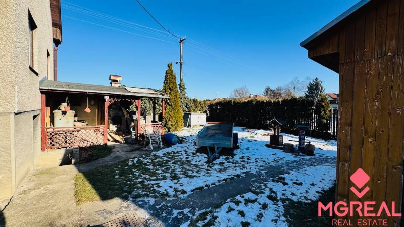 A családi ház kertje Nagybélen, Partizánske, fedett terasszal és havas gyepfelülettel.