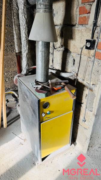 Kazánok a családi házban, szerszámokkal a tetején, egy befejezetlen helyiségben.