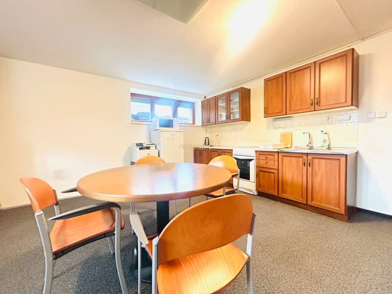 Konyha egy családi házban étkezőasztallal, székekkel és fa dekorációjú konyhabútorral.