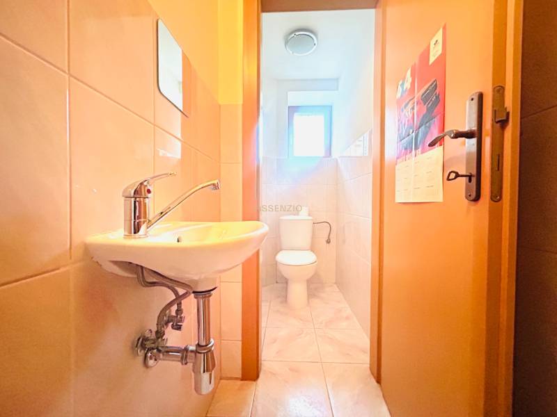 Fürdőszoba egy családi házban mosdóval, WC-vel és világos burkolattal a falakon.