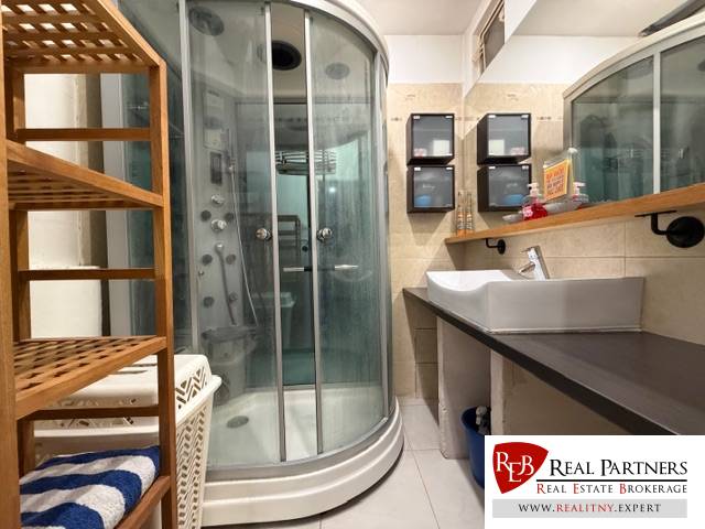 Fürdőszoba zuhanyzóval és mosdóval, fa dekorációval, 3 szobás lakás.