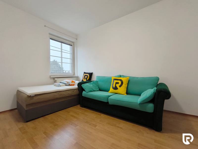 Szoba kanapéval és ággyal, fa dekoros padlóval, családi ház.