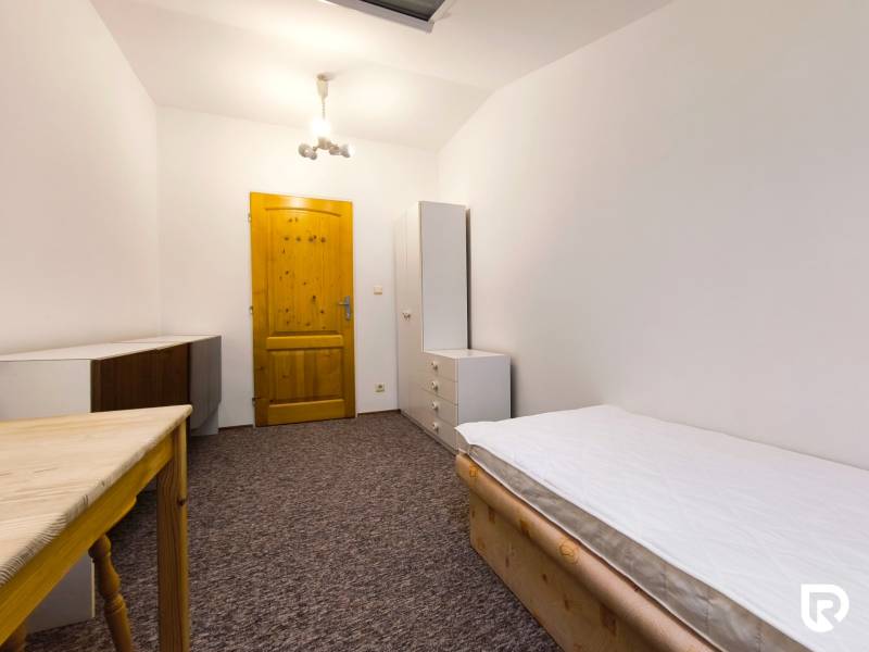 Szoba családi házban ággyal, szekrénnyel és asztallal, fehér világítással és szőnyegpadlóval kiegészítve.