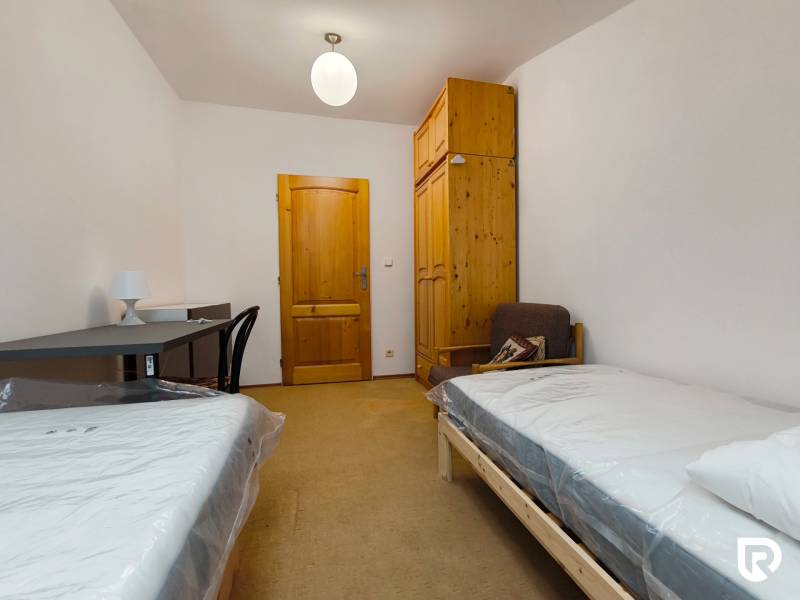 Szoba családi házban ágyakkal, asztallal, szekrénnyel és székkel.