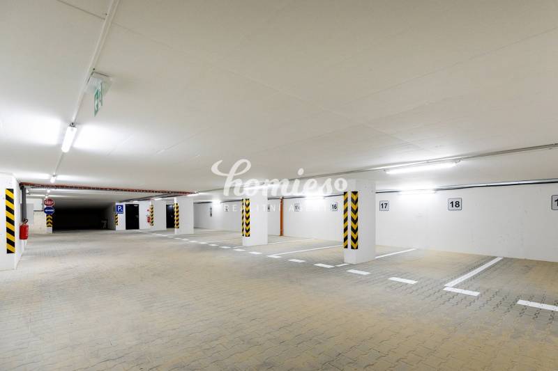 Földalatti parkoló világos világítással és kijelölt parkolóhelyekkel.