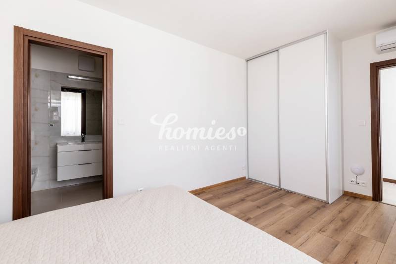 Hálószoba egy háromszobás lakásban fa dekor padlóval és beépített szekrénnyel.