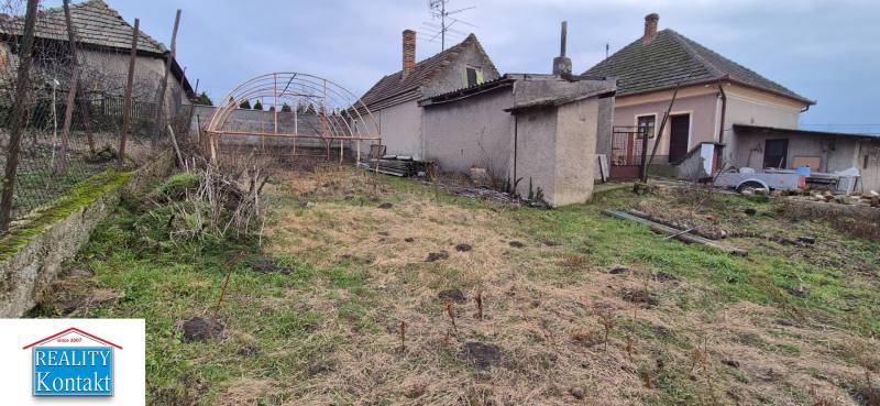 Családi ház kertje Udvardon, elhanyagolt telekkel és üvegház szerkezettel.