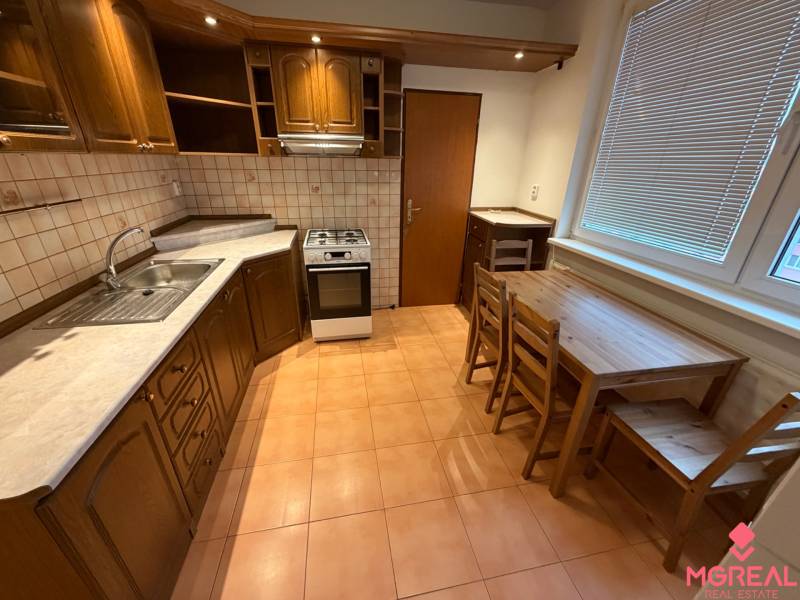 3 szobás lakás konyhája fa dekorú szekrényekkel és étkező ülőgarnitúrával.