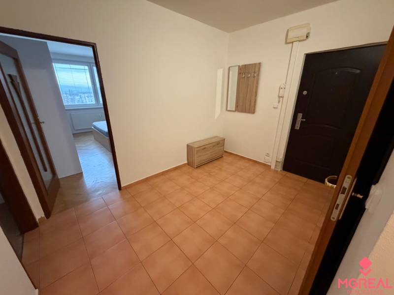 A háromszobás lakás előszobája kerámia padlóval, fogassal és kilátással a szobára.