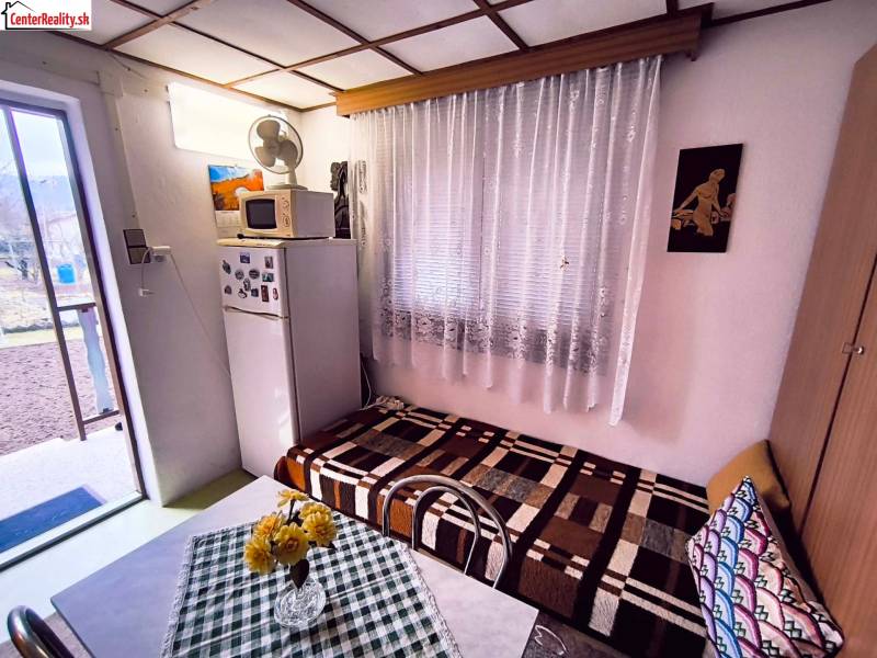 A ház belseje hűtőszekrénnyel, kanapéval, asztallal és kilátással a kertre.