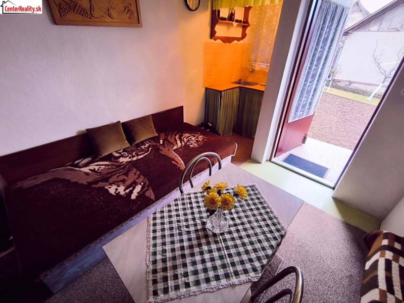 A ház belseje kanapéval, étkezőasztallal és a kertbe nyíló ajtókkal.