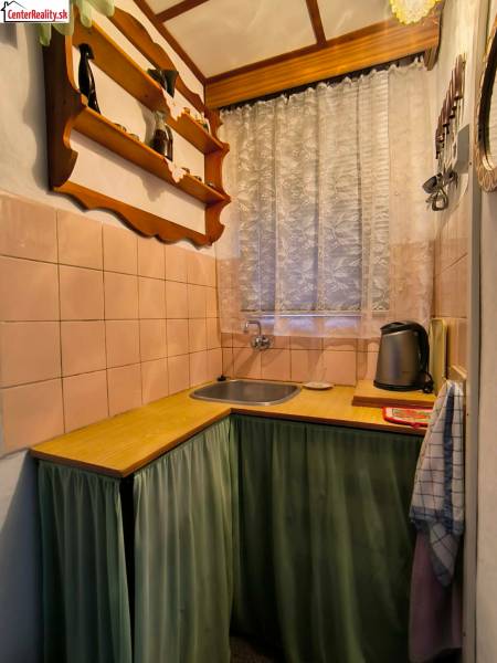 Konyha fahatású dekorral, polccal és függönnyel az ablaknál.