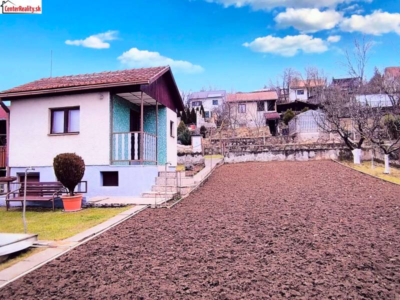 Ház Partizánske-ban kerttel és frissen szántott földdel, paddal és bokrokkal.