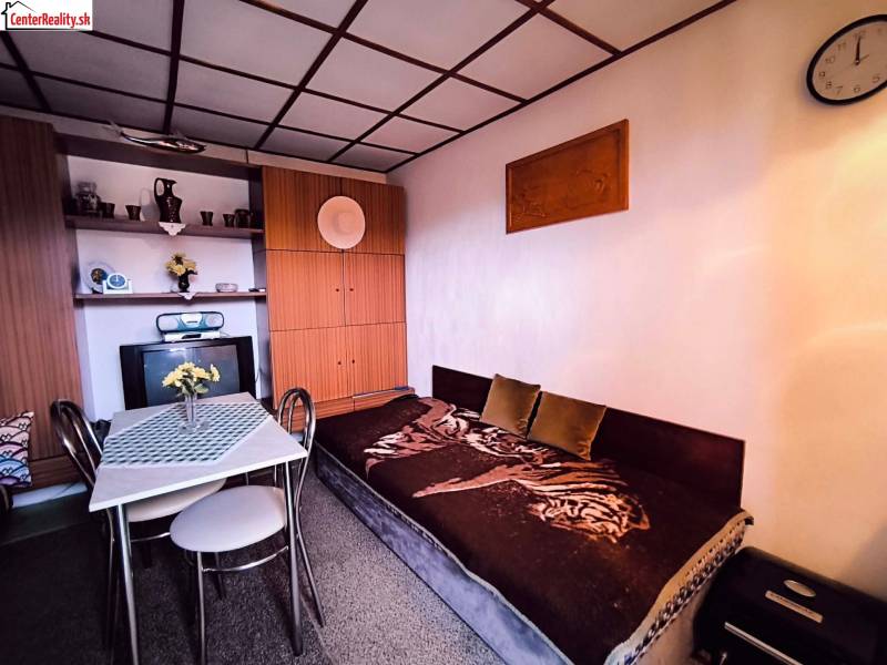 A ház belső tere kanapéval, étkezőasztallal és beépített szekrénnyel, természetes színpalettával dominál.