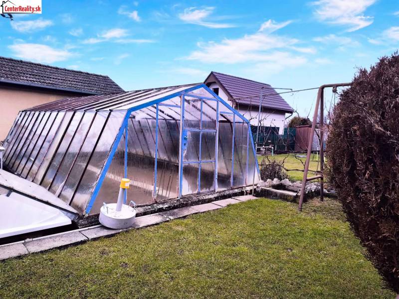 Kert Partizánske-ban, föld feletti medencével, amelyet szerkezet fed le, hinta, zöld gyep.