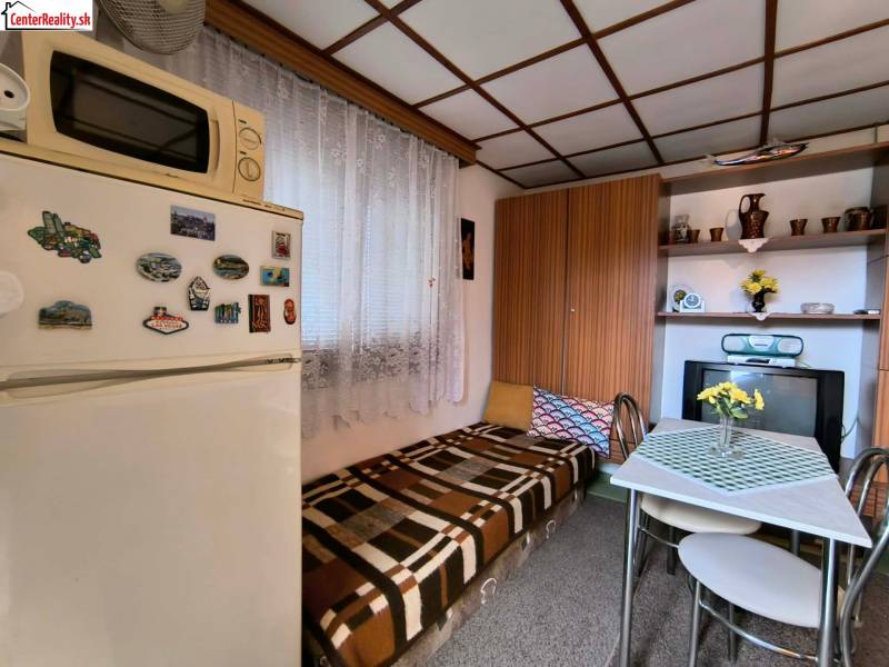 Egy kis konyha a faházban, fa dekorációval, étkezőasztallal és hűtőszekrénnyel.