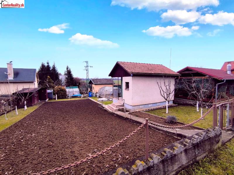 Partizánskei ház külső része rendezett kerttel, gyepesített területtel és virágágyással.