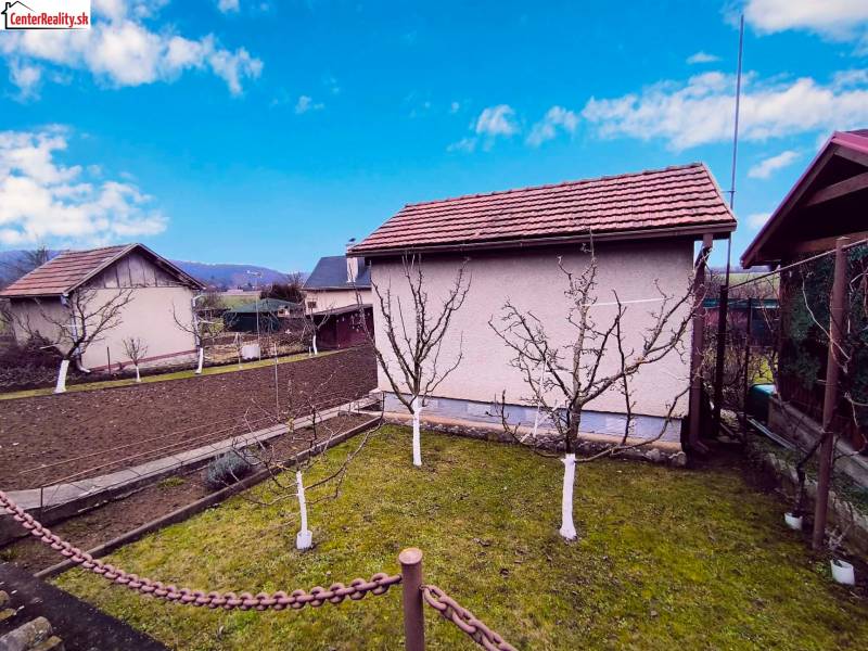 Kert házzal Partizánske városában, gyümölcsfák és megművelt föld, tiszta égbolt.