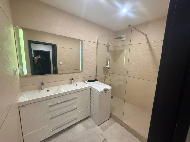 Fürdőszoba dupla mosdóval, zuhanyzóval és mosógéppel egy háromszobás lakásban.