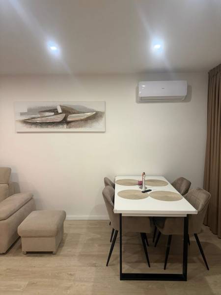 Ebédlő egy 3 szobás lakásban, fa dekor padlóval, asztallal és székekkel.