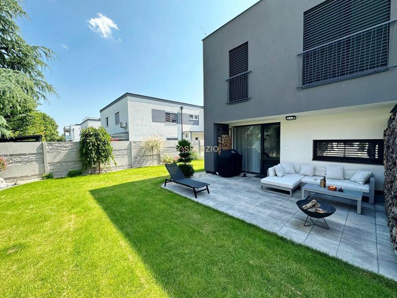 Családi ház Rovinkában terasszal, zöld gyepfelülettel és kerti ülőhellyel.