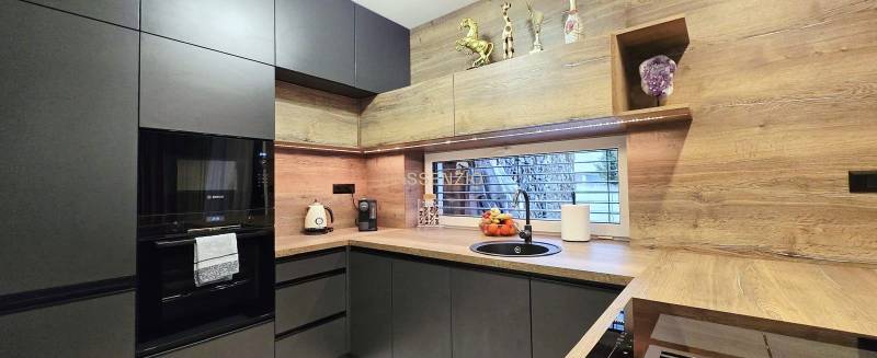 Konyha egy családi házban sötét szekrényekkel és fa dekoros padlóval.