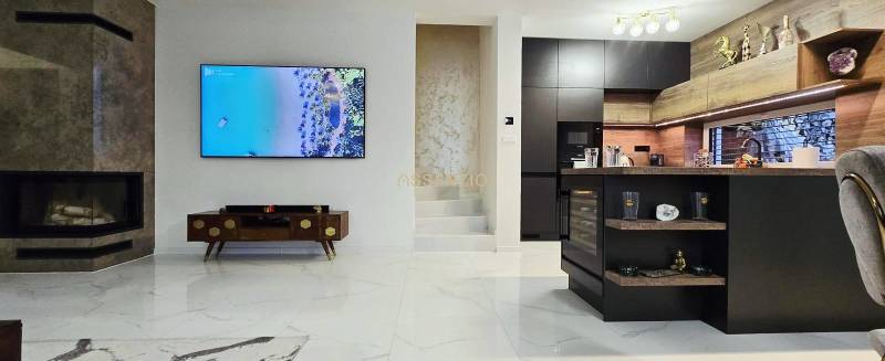 Nappali családi házban kandallóval és konyhaszigettel, fa dekorációjú padlóval.