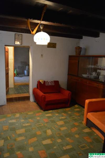 Nappali egy családi házban, piros fotellel és edényes szekrénnyel.