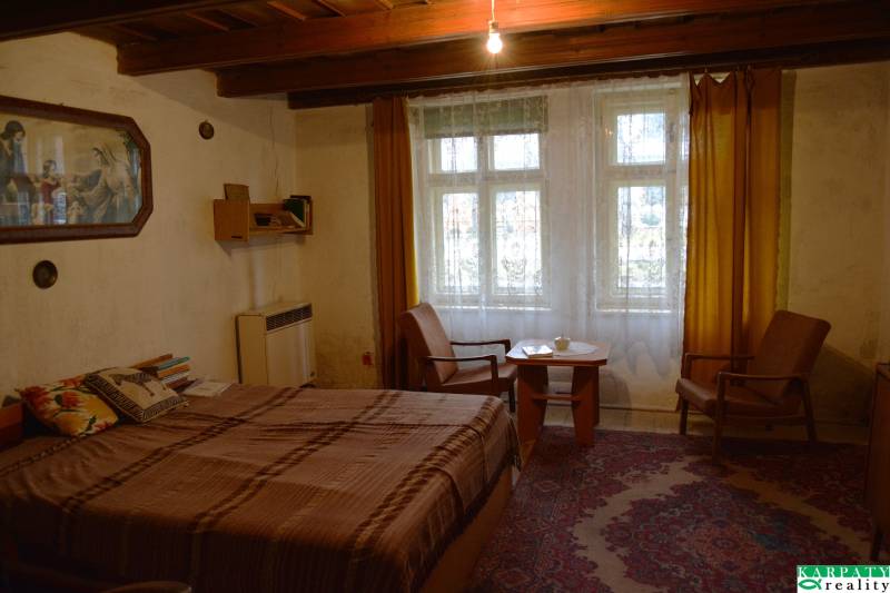 Szoba családi házban ággyal, székekkel, sárga függönyökkel és szőnyeggel.