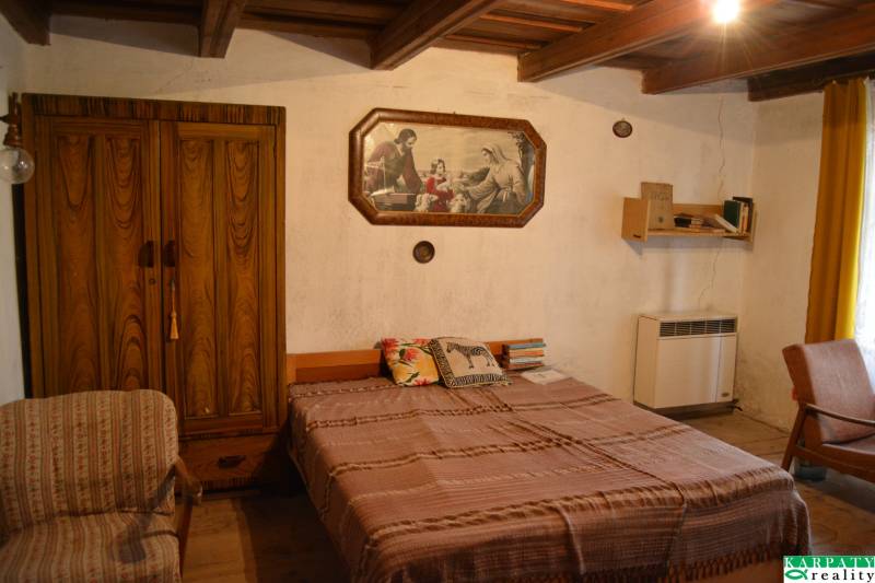 Hálószoba egy családi házban fa szekrénnyel, ággyal és képpel a falon.