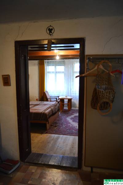 Családi ház belső tere ággyal és fa padlóval, az ajtón keresztül látható egy szoba.