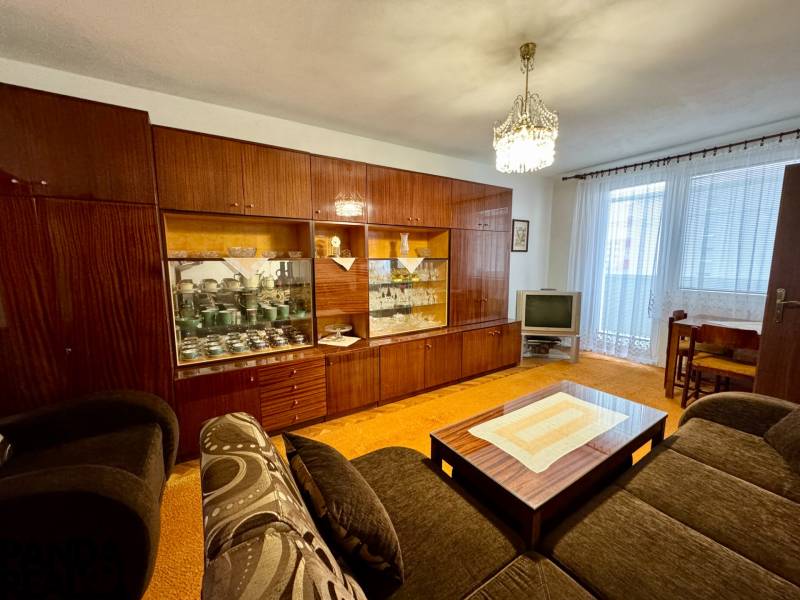 Nappali rusztikus nappali falakkal és TV-vel egy háromszobás lakásban.