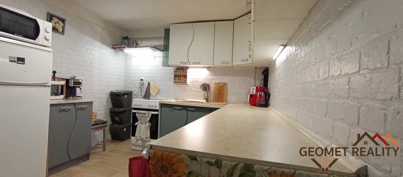 Konyha egy családi házban fehér téglafalakkal és konyhai készülékekkel.