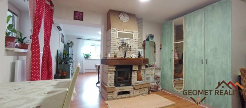 Családi ház belső tere kandallóval és fa dekorációjú padlóval, kiegészítve színes díszítéssel.