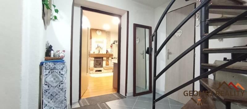 Családi ház belső tere lépcsőházzal, fa dekorációjú padlóval és kandallóval.