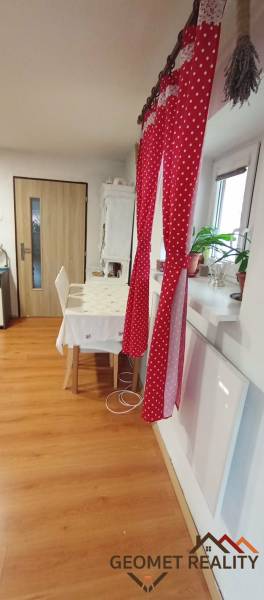 Ebédlő egy családi házban piros függönnyel, asztallal és fa dekorációjú padlóval.