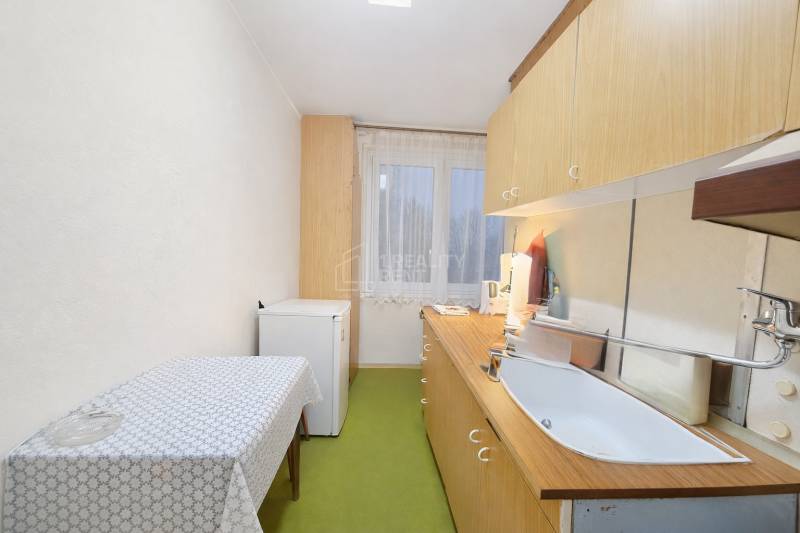 Konyha egy 3 szobás lakásban egyszerű berendezéssel, fa dekoros padlóval.