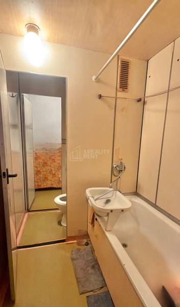 Fürdőszoba egy háromszobás lakásban káddal és mosdóval.