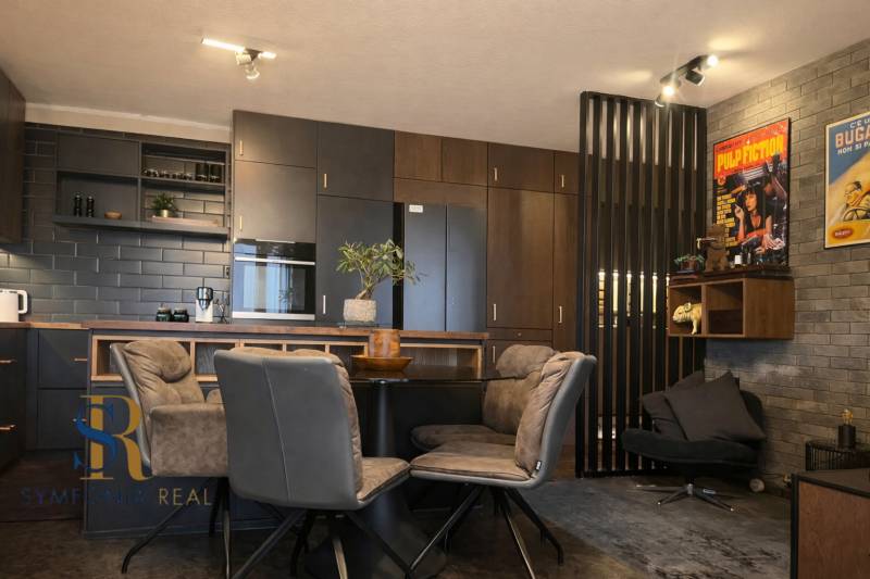 Konyha egy kétszobás lakásban sötét szekrényekkel és dekoratív poszterekkel a falon.