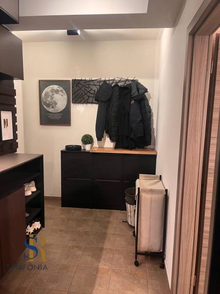 Előszoba egy 2 szobás lakásban praktikus bútorokkal és a falon lévő hold dekorációval.