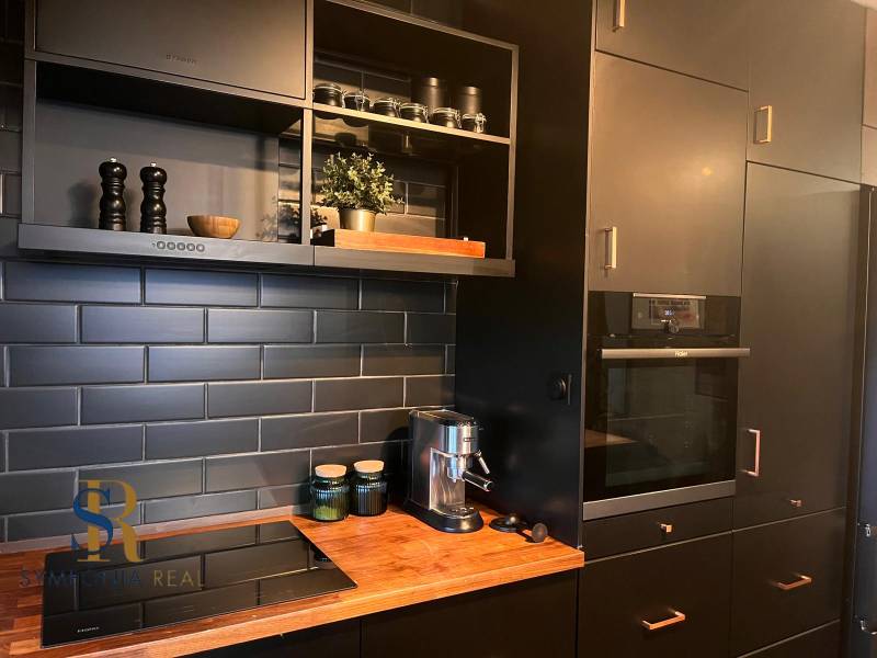 Konyha fekete szekrényekkel egy kétszobás lakásban, fa mintázatú padlóval.