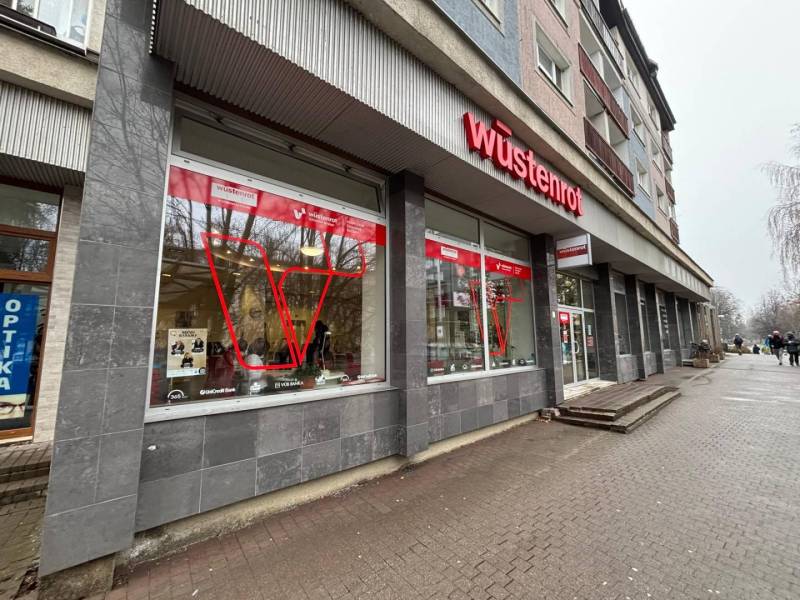 Kereskedelmi helyiségek Poprádon, feltűnő piros logóval az épületen.