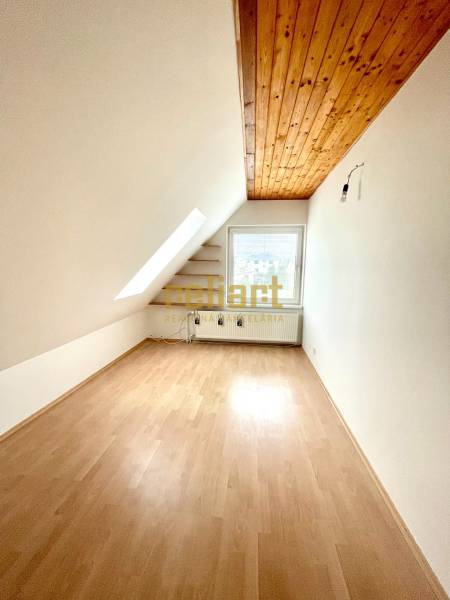 Tetőtéri szoba családi házban, fa dekoros padlóval és tetőablakkal.